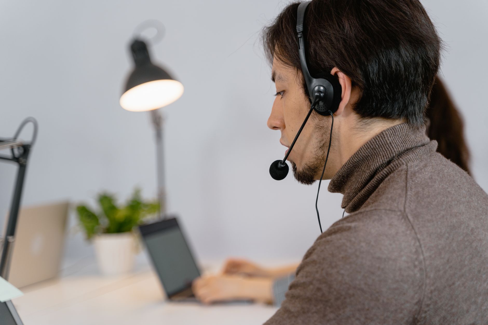 Customer support professional using headset at laptop