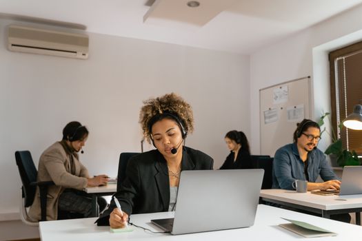 Team of call center agents working diligently with headsets and laptops in a modern office setting.