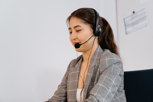 Photo of a Woman in a Black and White Blazer Wearing a Black Headset