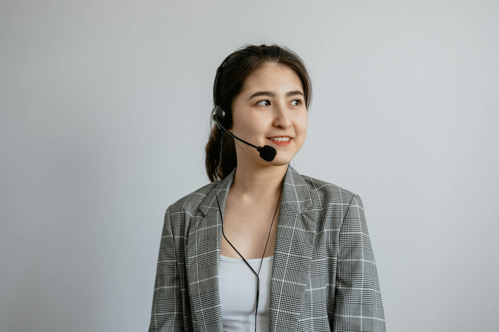 Smiling young woman in a call center wearing a headset ready to assist customers.