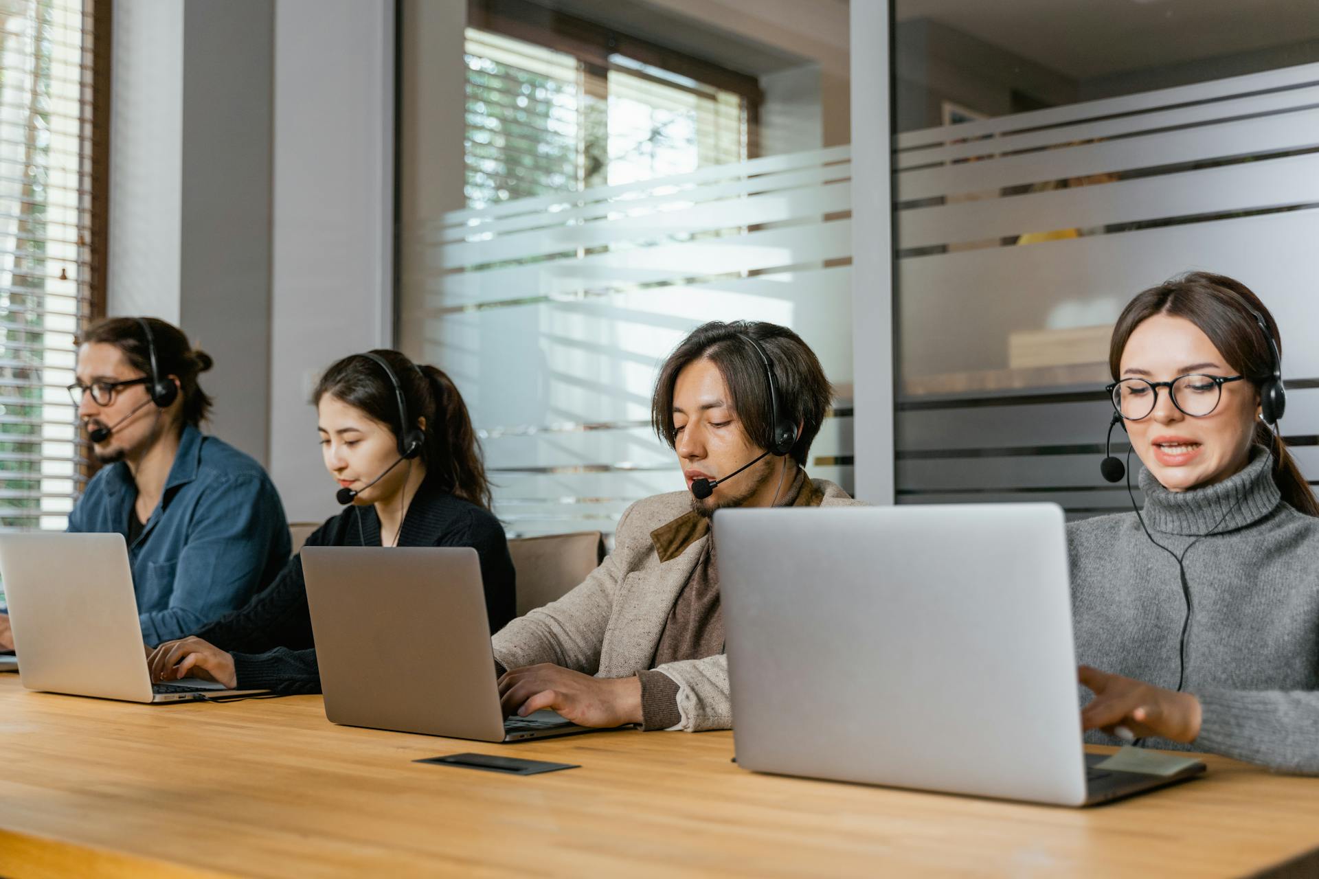 Four customer support agents working diligently in an office setting.