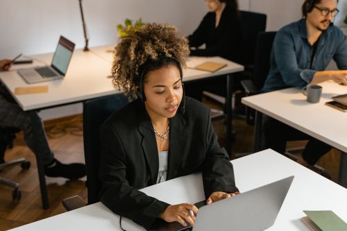 Free Customer support representative working diligently at a laptop in a modern office environment. Stock Photo