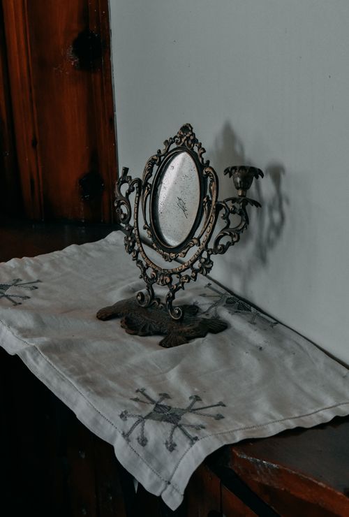 Free An antique mirror with intricate design on a decorated cloth creating a classic vintage ambiance. Stock Photo