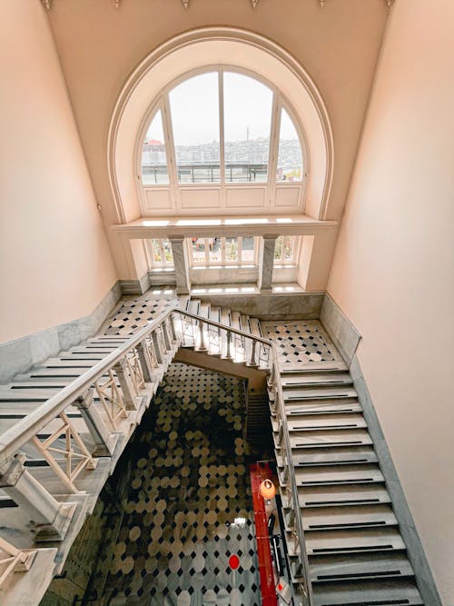 Free High angle of stone stairway with railing inside of old building with classic design and arched window Stock Photo