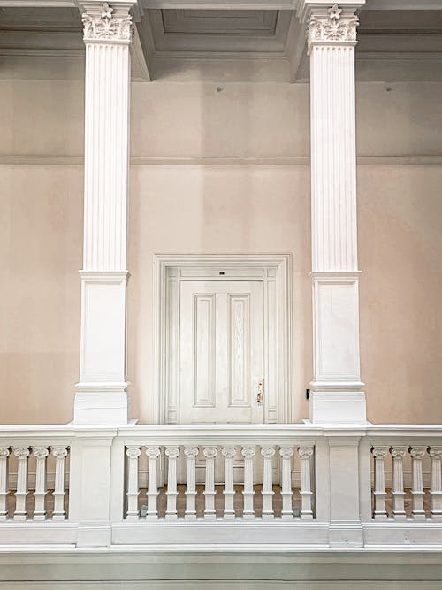 Free White pillars and railing on gallery with white doorway in classic interior of old building Stock Photo