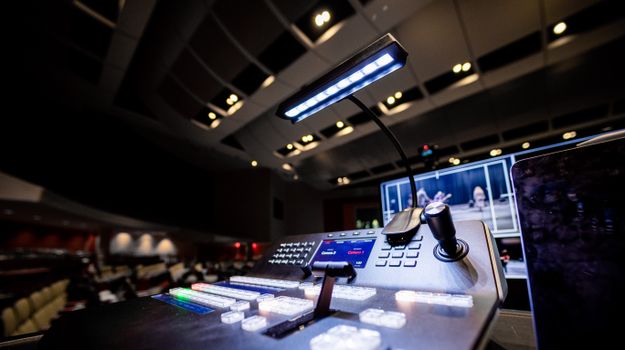 Contemporary music console with buttons and glowing lamp under ceiling with lights in dark studio