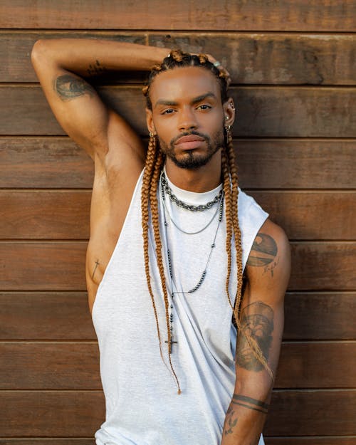 Photo of a Man with Braided Hair Posing with His Hand on His Head