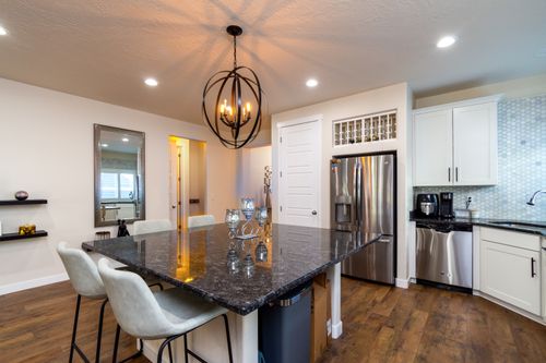 Free Spacious kitchen featuring a granite island, pendant lighting, and stainless steel appliances. Stock Photo