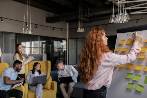 Free Team members collaborating in a modern office, focusing on strategy and planning using sticky notes. Stock Photo