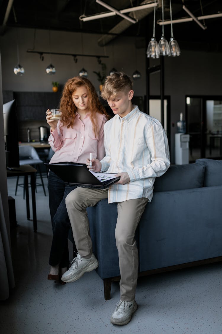 Photo Of A Man In A White Shirt Showing His Laptop To A Woman In A Pink Shirt