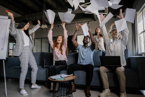 Free A diverse group of coworkers celebrating success by throwing papers in an office. Stock Photo