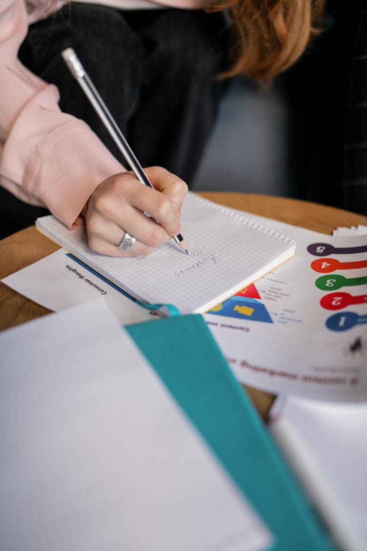 A Person With A Ring Writing On A Notebook