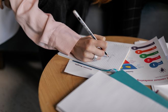 A researcher writing study notes beside printed charts — photo by Alena Darmel on Pexels