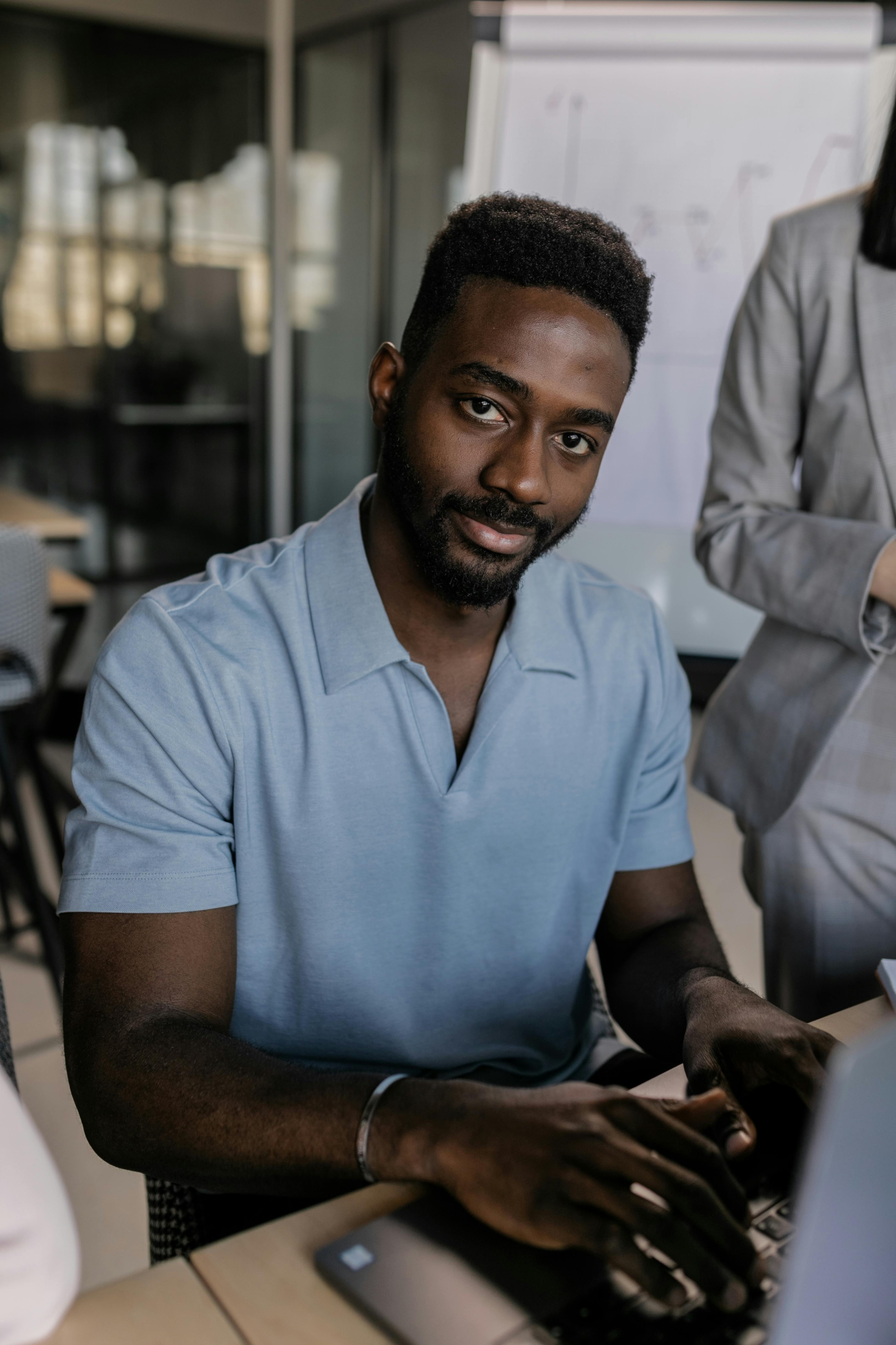 selective focus photo of a man in a blue polo shirt typing on a laptop