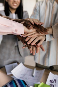 A close-up of diverse hands joined together symbolizing teamwork in an office setting.