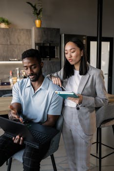 Two professionals collaborating in a contemporary office setting with a laptop.
