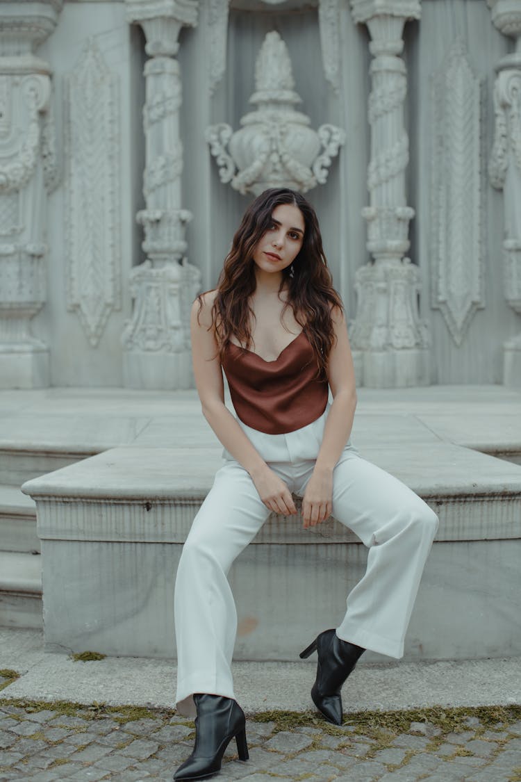 Female Sitting On Background Of White Marble Bas Relief