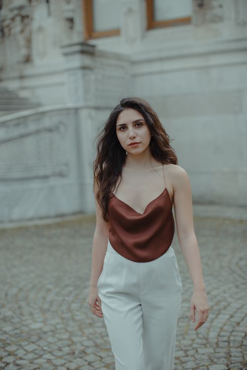 Free Elegant woman with brown hair posing in a cityscape, showcasing urban fashion and style. Stock Photo