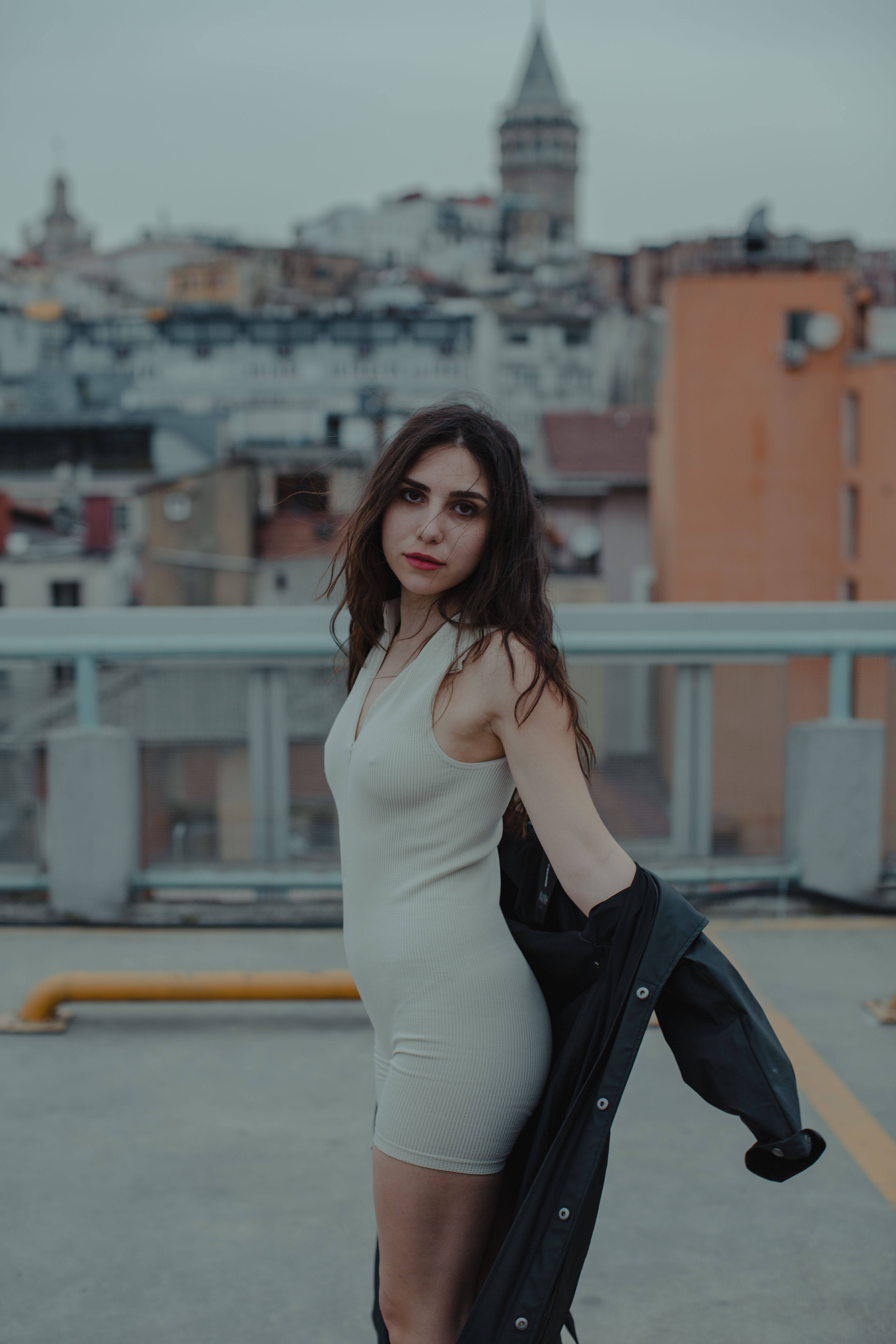Stylish woman posing on an Istanbul rooftop with a cityscape background.