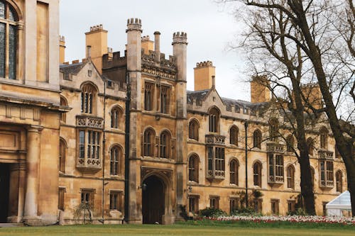 Free Elegant historic building facade with Gothic architecture and lush garden setting outdoors. Stock Photo