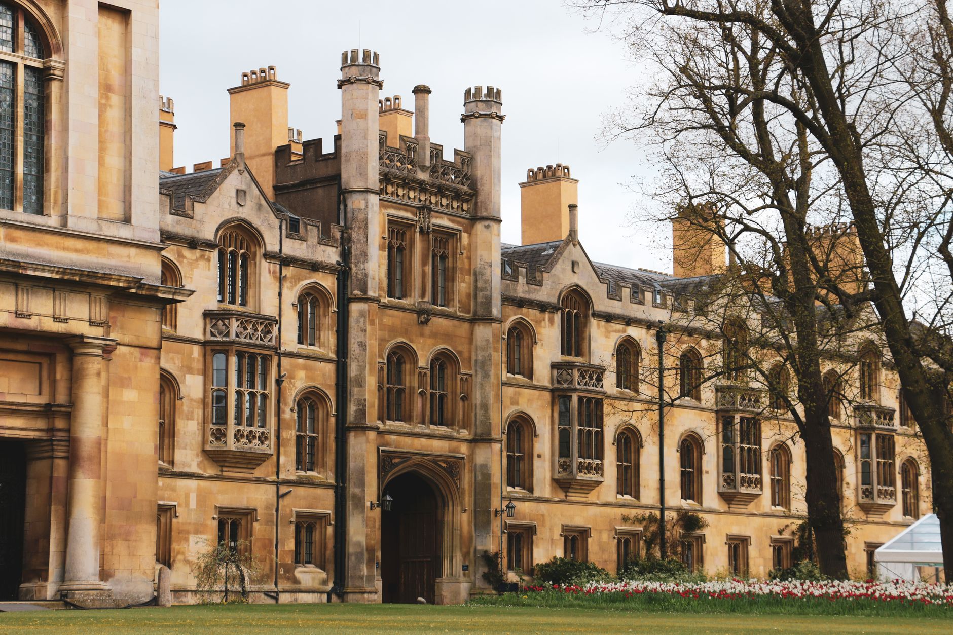 Elegant historic building facade with Gothic architecture and lush garden setting outdoors.