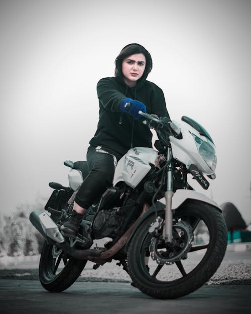 A Woman in Black Hoodie Riding a Motorcycle