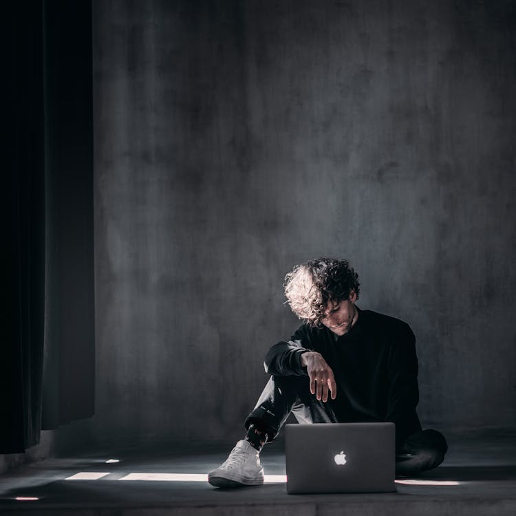 Young Man Using Laptop On Floor