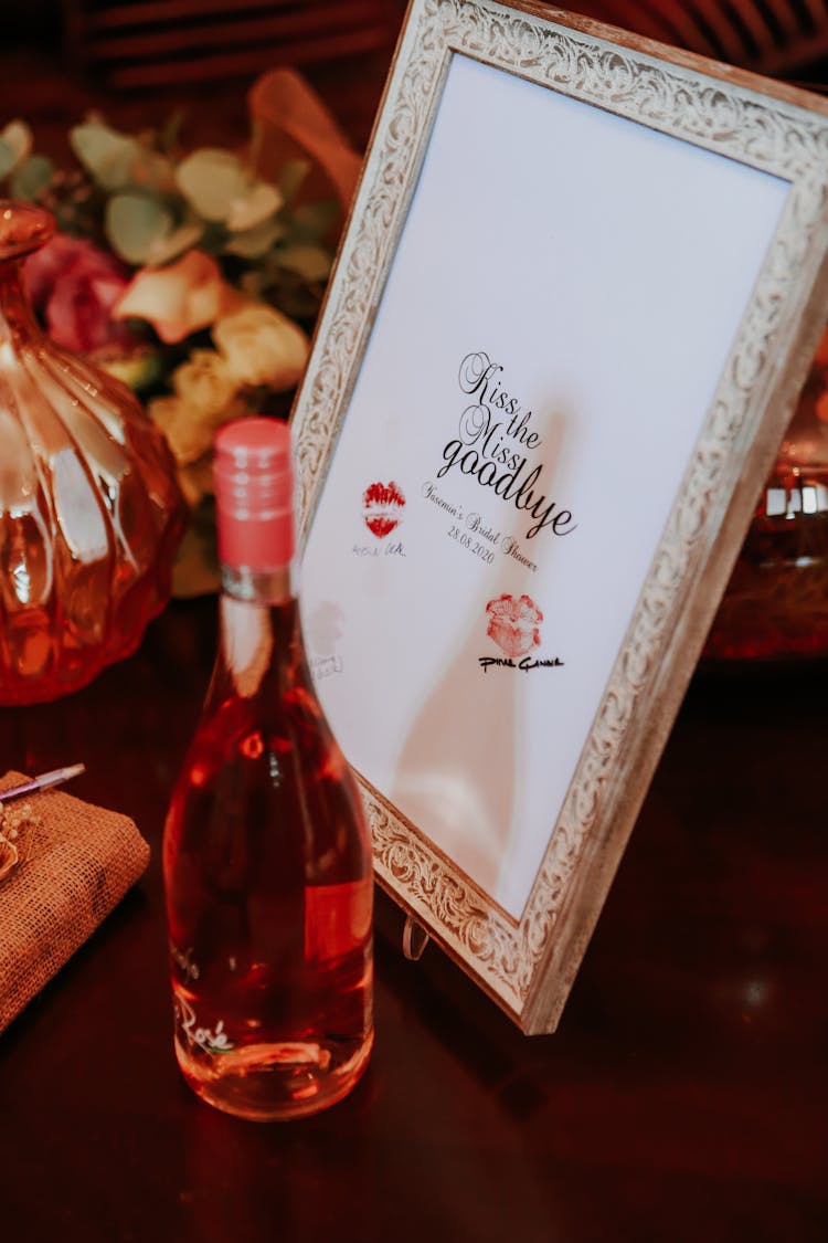 Wine Bottle And Framed Picture With Kisses Placed On Table During Hen Night