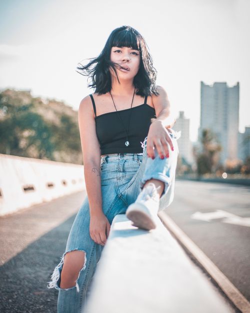Free Stylish young woman with black hair sitting on a city barrier in São Paulo, Brazil. Stock Photo