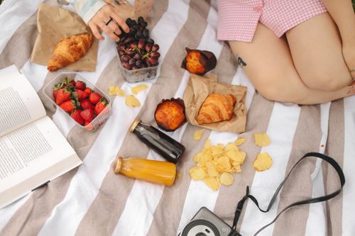 Free Relaxing picnic with croissants, strawberries, grapes, and juice on a striped blanket. Perfect for outdoor leisure. Stock Photo