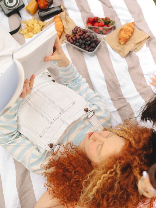 A Woman with Curly Hair Reading a Book in a Picnic