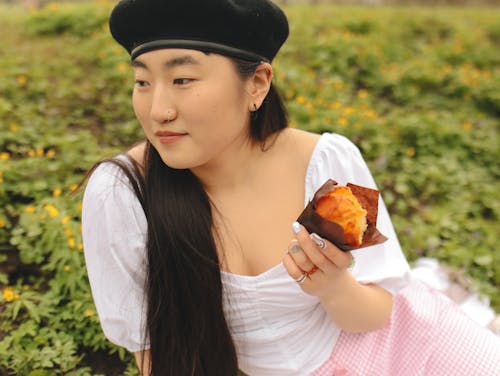 

A Woman Wearing a Beret Holding a Muffin