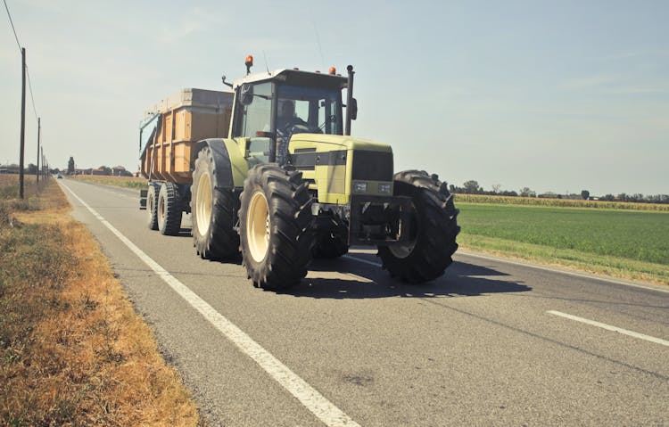 Yellow Tractor In Asphalt Road