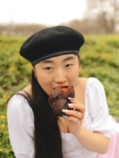 Kostenloses Stock Foto zu asiatische frau, baskenmütze, essen