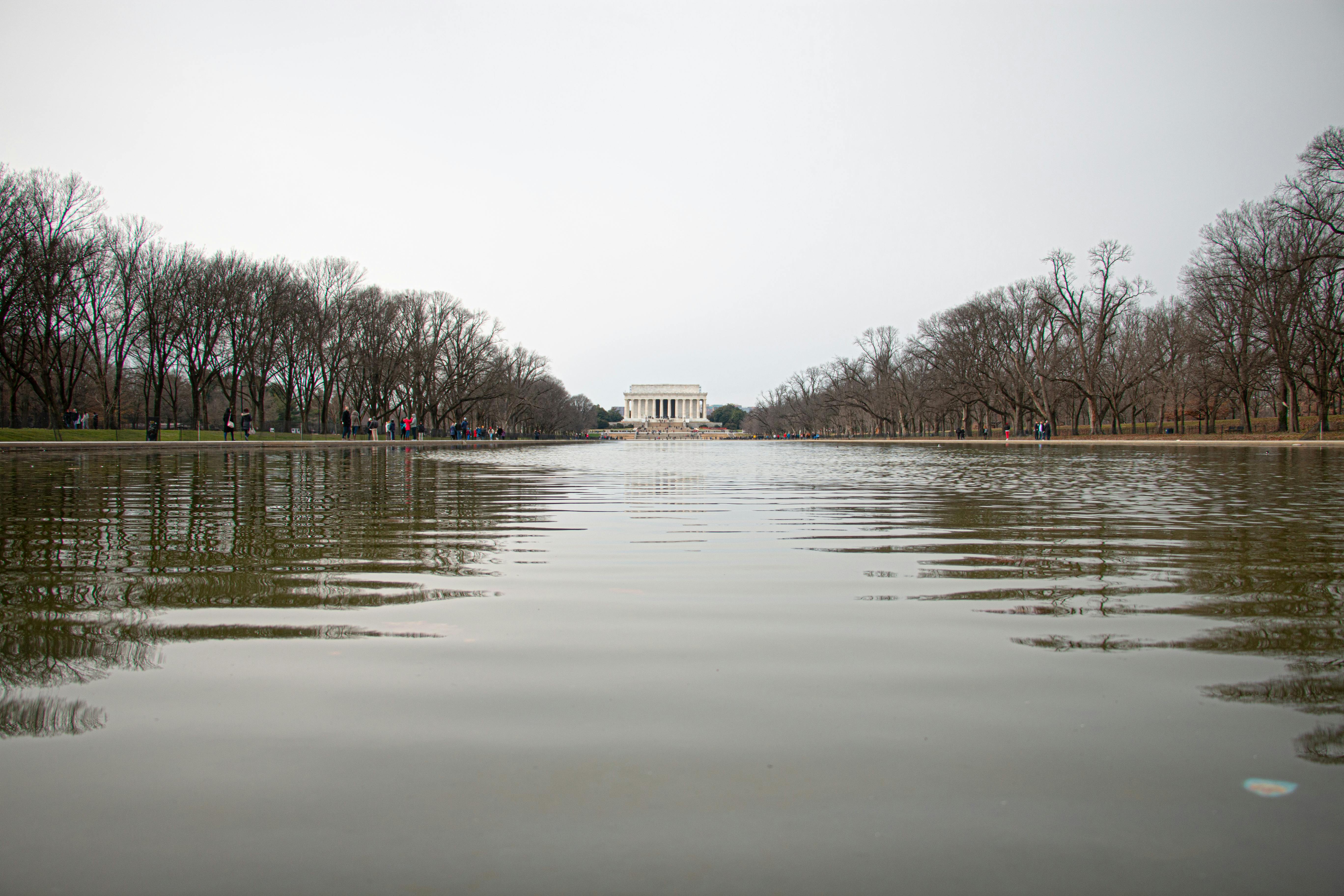 Serene view of the Lincoln Memorial reflected on the Tidal Basin with winter trees lining the edges.