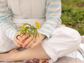 Woman in White Long Sleeve Shirt Holding Yellow Flowers