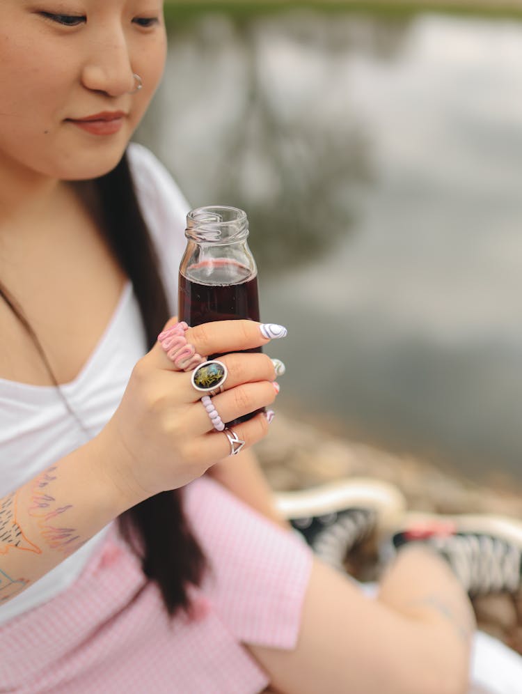 A Woman Holding A Bottle Of Drink