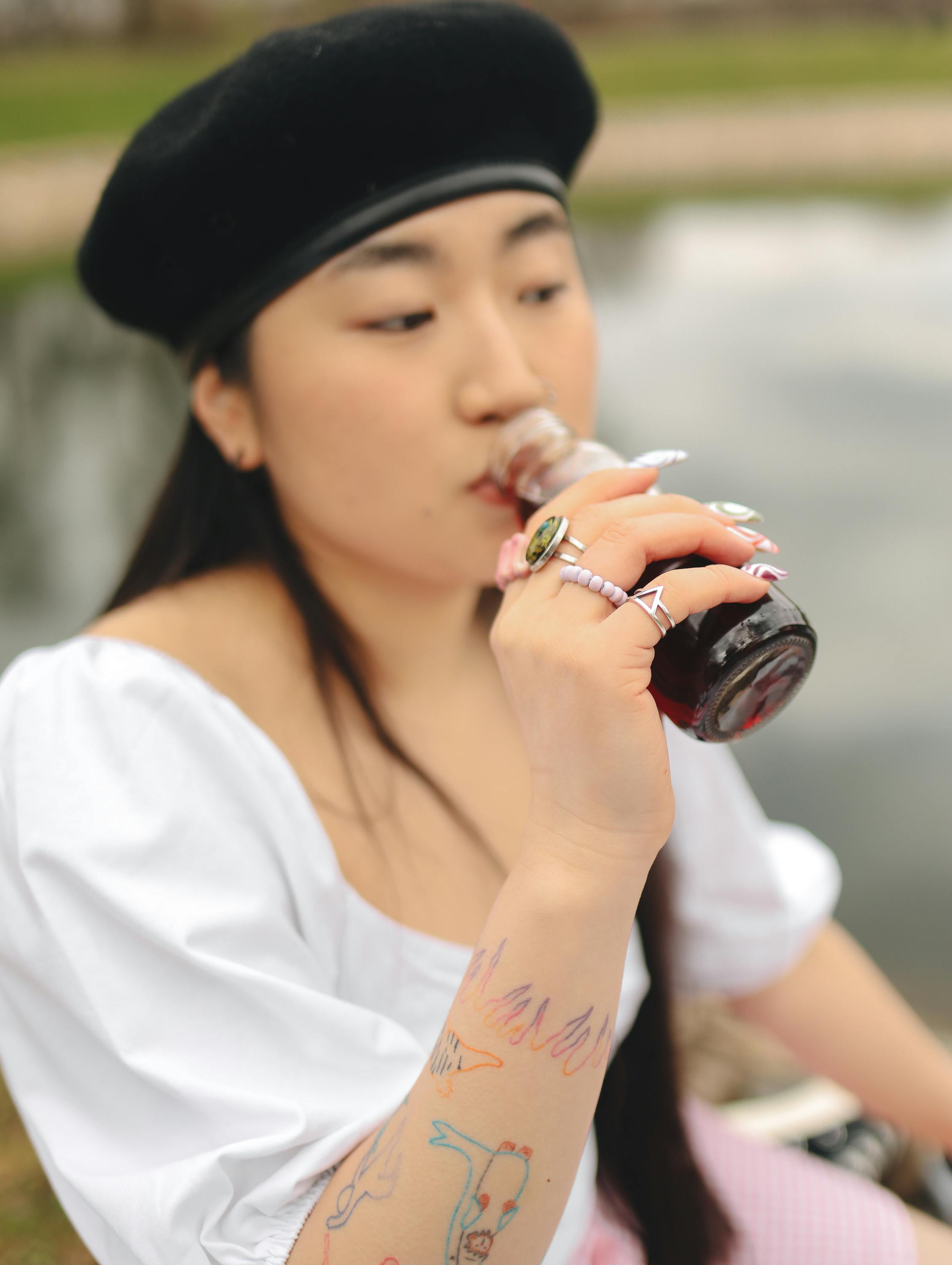 Woman Drinking From Glass Bottle with Colored Liquid · Free Stock Photo