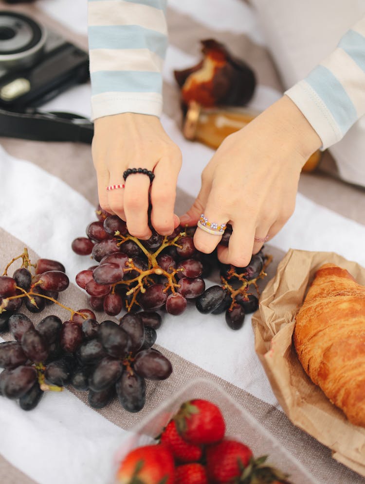 Hands Picking Grape On The Picnic Blanket