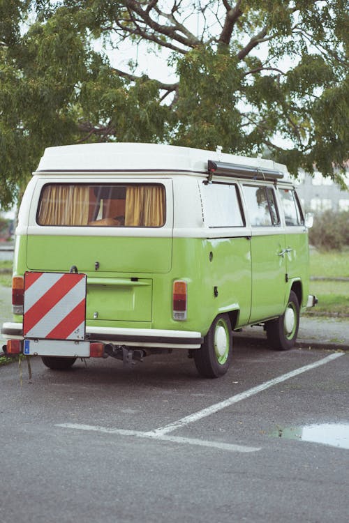 A Green Camper Van Parked Below a Tree