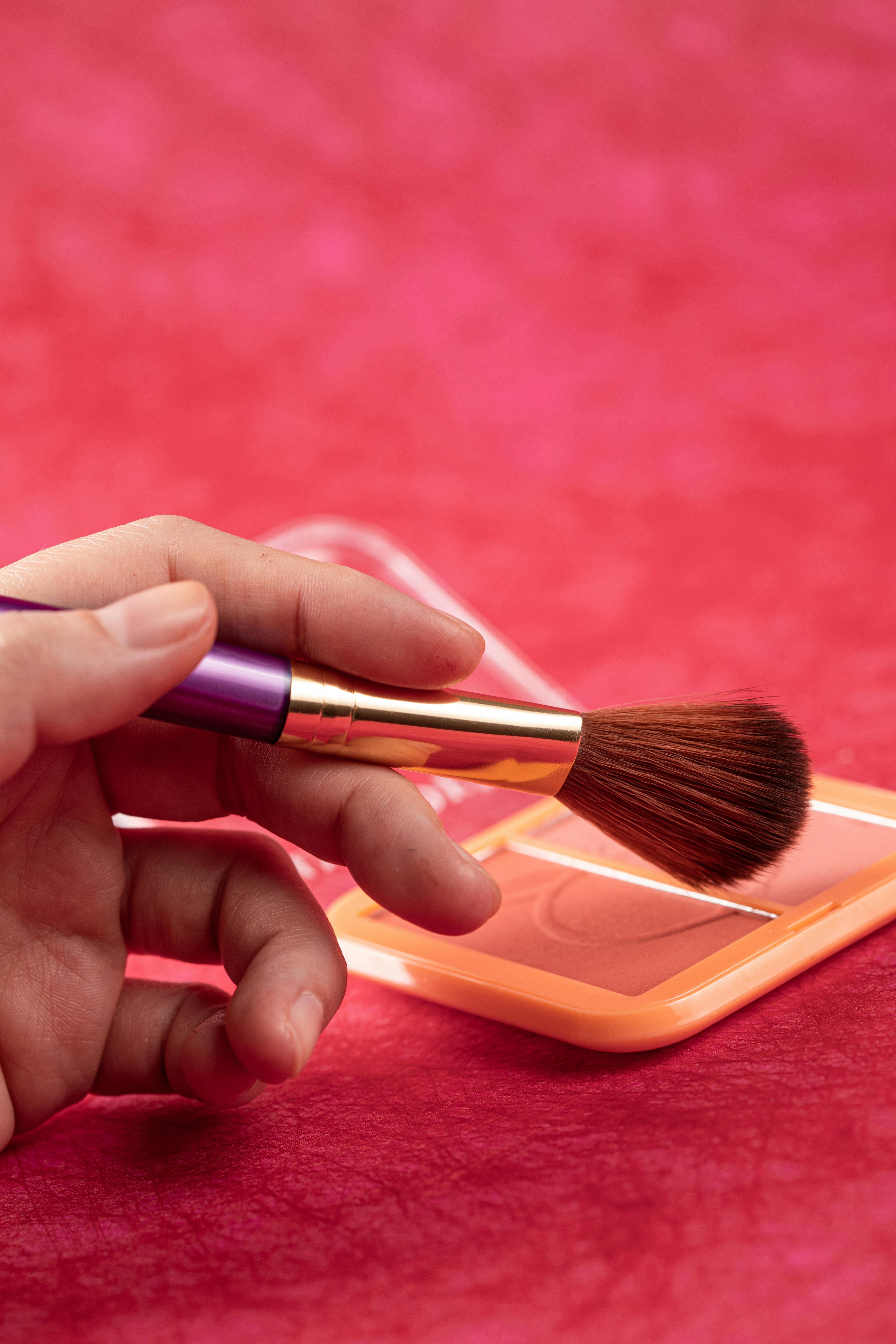 person holding black and brown makeup brush