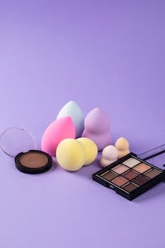 Colorful makeup sponges and cosmetics set against a stylish purple backdrop.