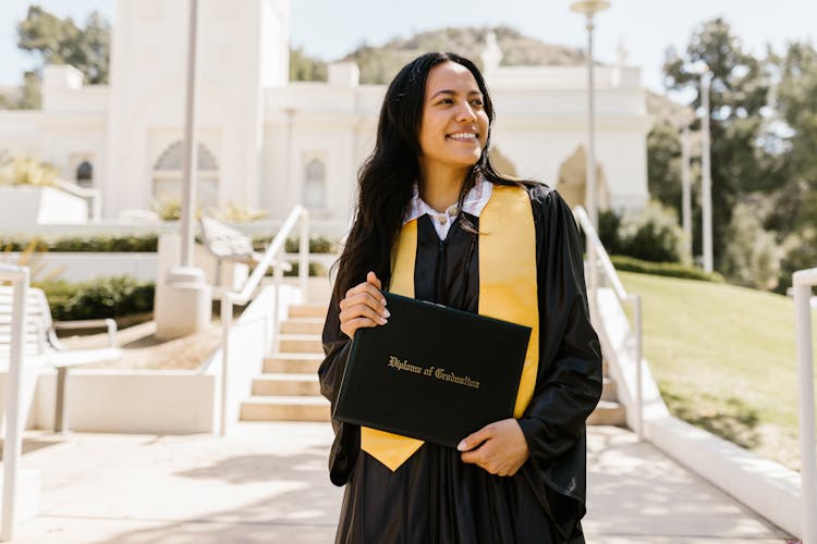 Woman Wearing Graduation Gown Holding A Diploma