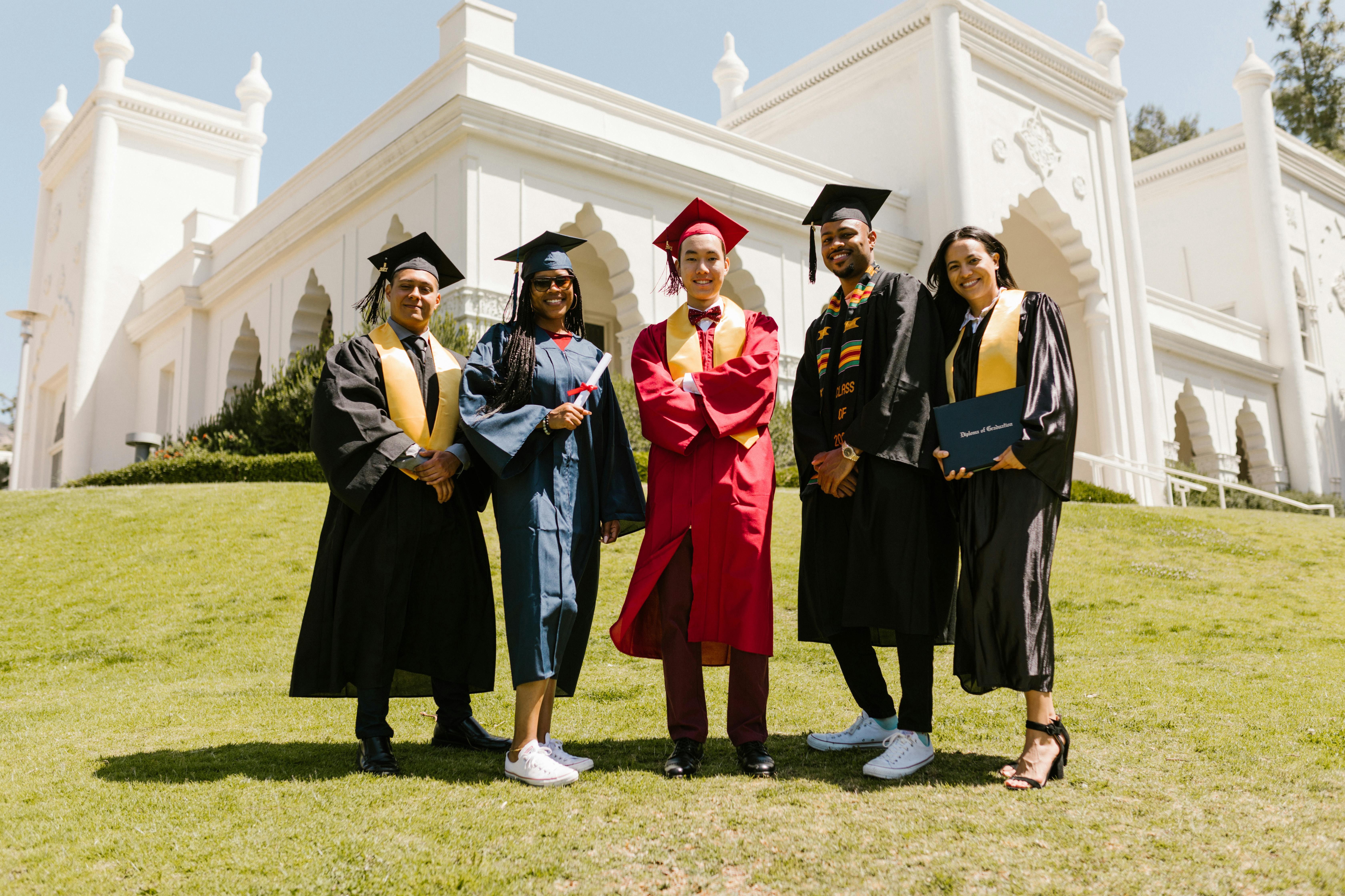 Five graduates celebrate together on campus, representing how higher education levels connect to longer life expectancy.