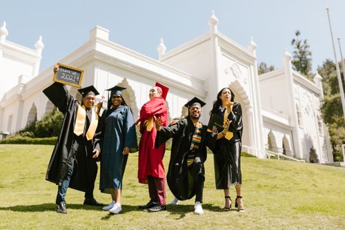 Free Group of diverse students celebrating graduation outdoors with excitement. Stock Photo