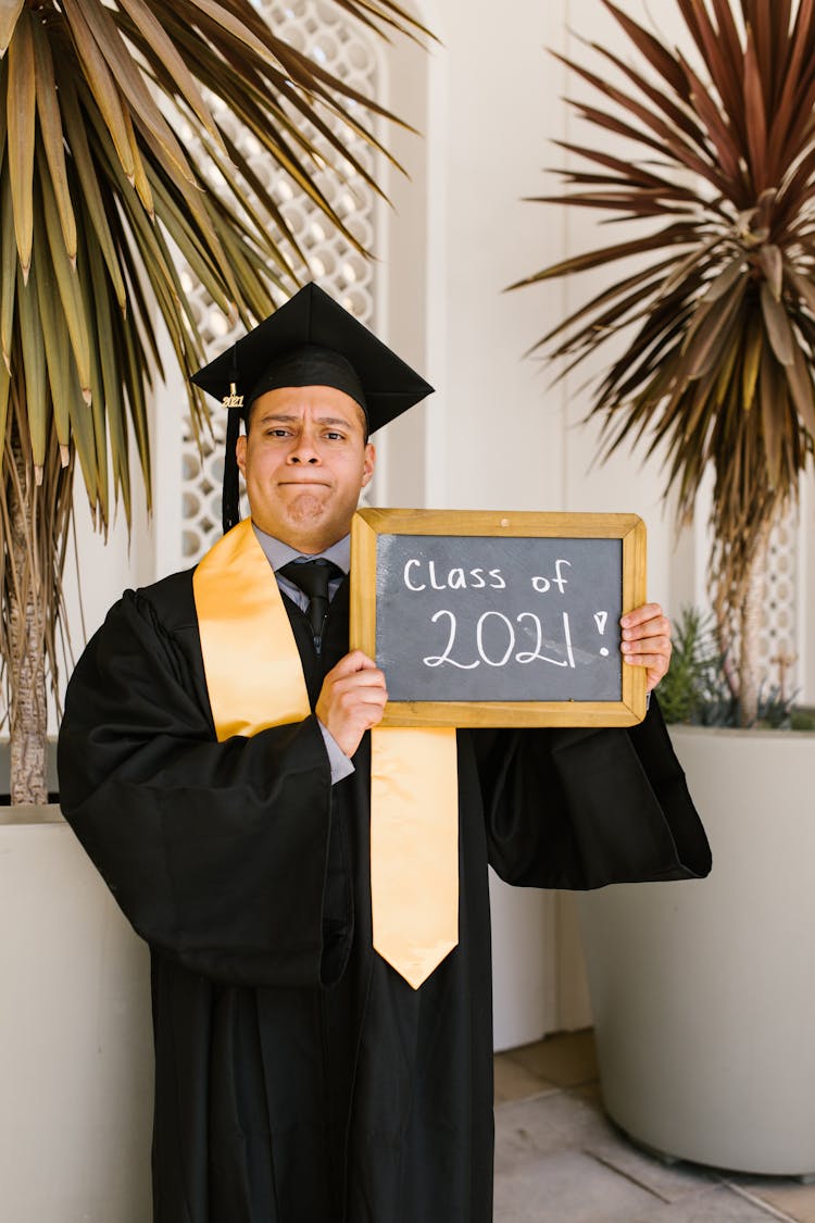 A Man In Academic Regalia Holding A Frame