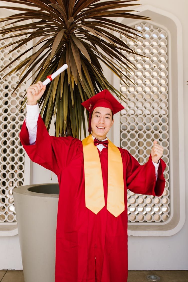 A Newly Graduate Man Holding A Rolled Certificate While Smiling At The Camera