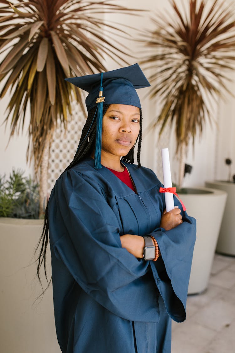 Woman In Blue Toga Holding A Rolled Certificate While Seriously Looking At The Camera