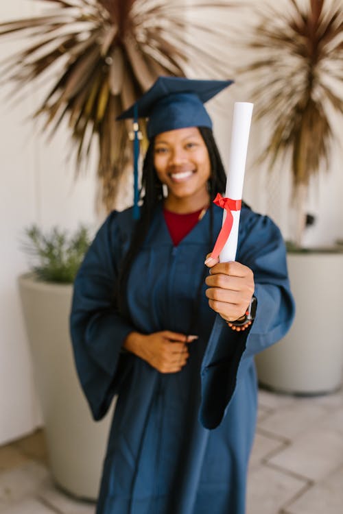 A Woman in Academic Regalia Smiling while Holding a Diploma · Free ...
