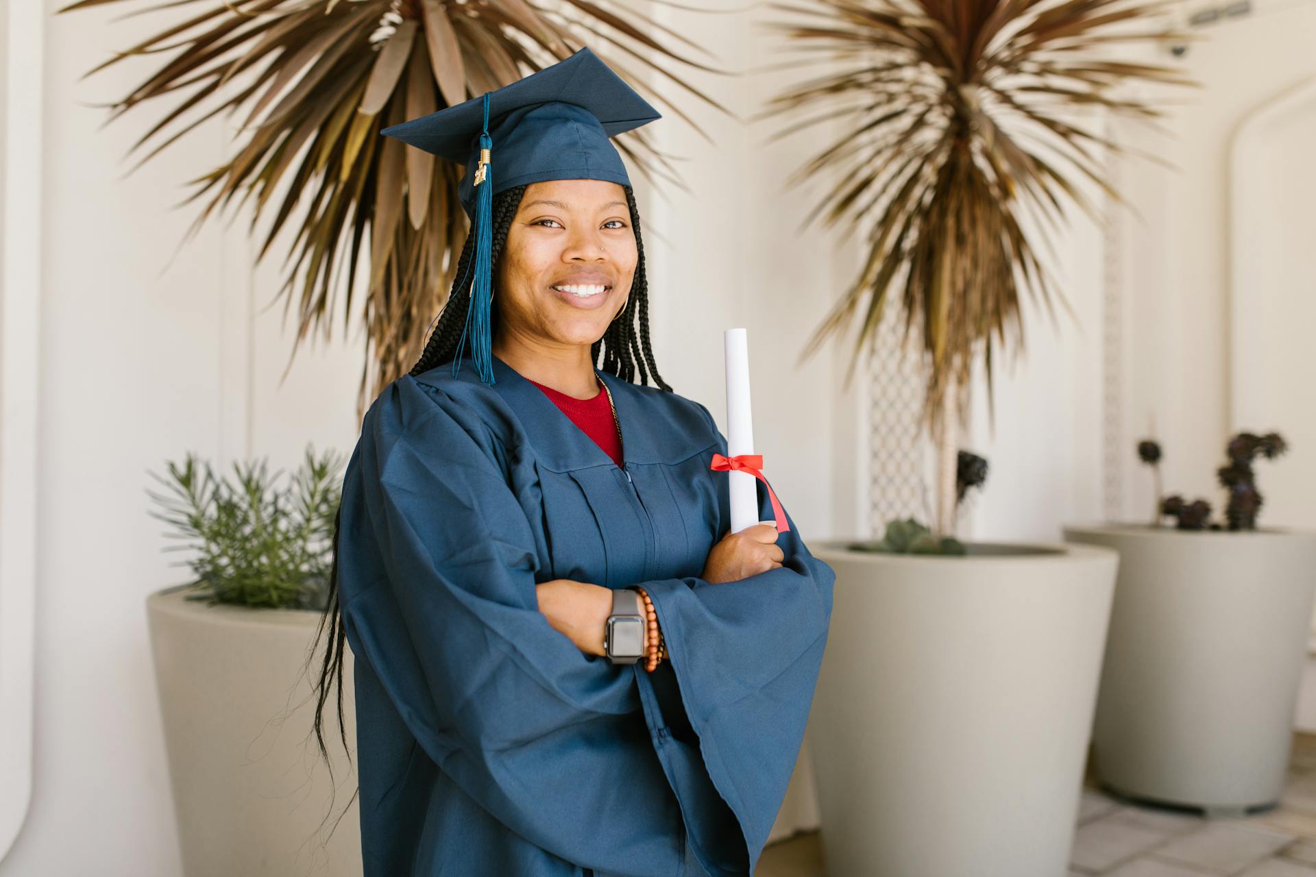 Woman in Academic Gown Holding a Rolled Certificate while Smiling at the Camera